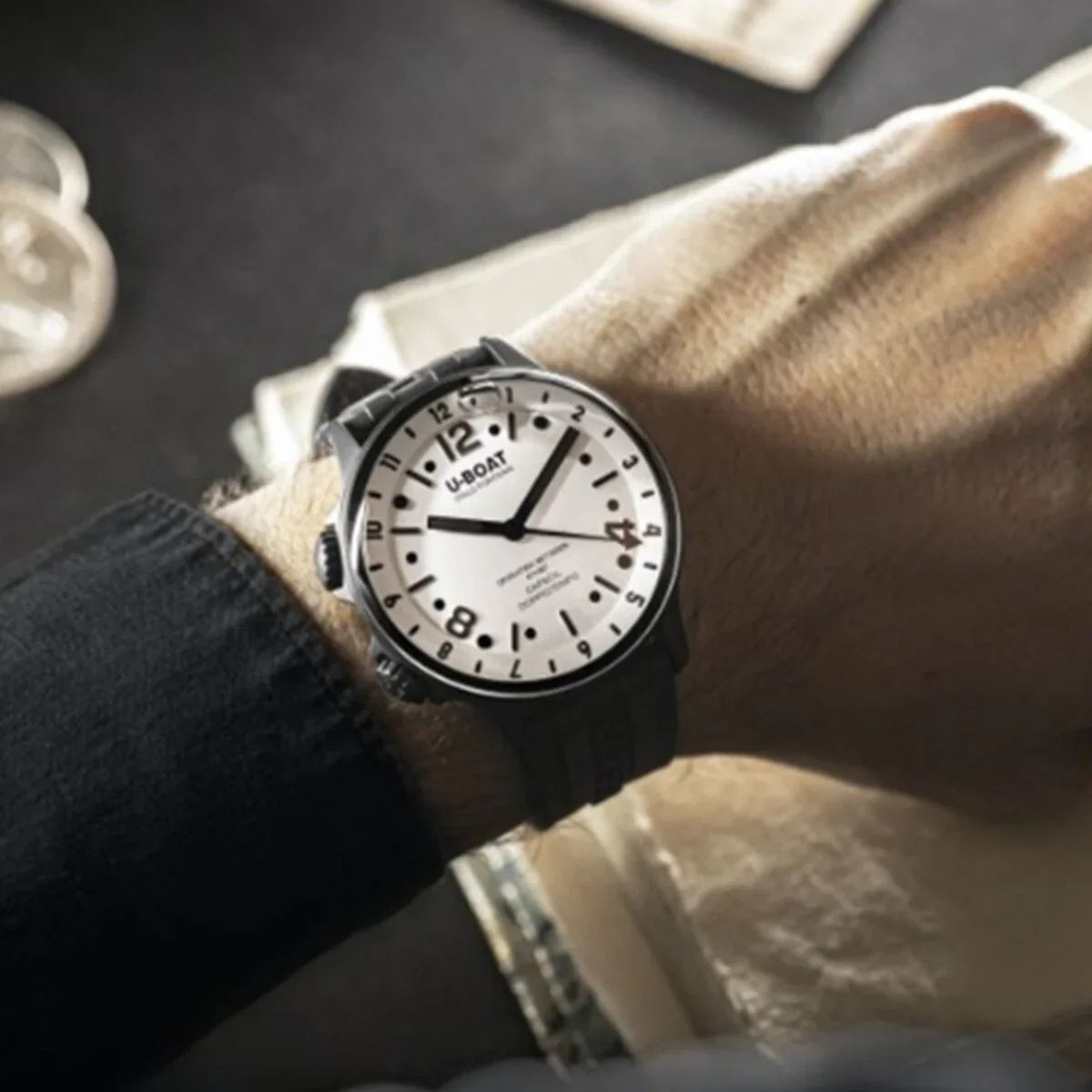 Caol na bhfear ag caitheamh faire dhiailiú mór bán le uimhreacha trom dubh agus strap dubh uigeach