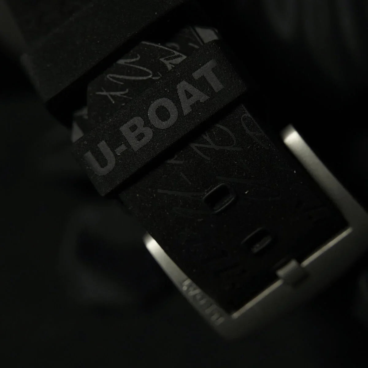 Close-up of a black U-Boat watch strap and silver buckle on a dark background