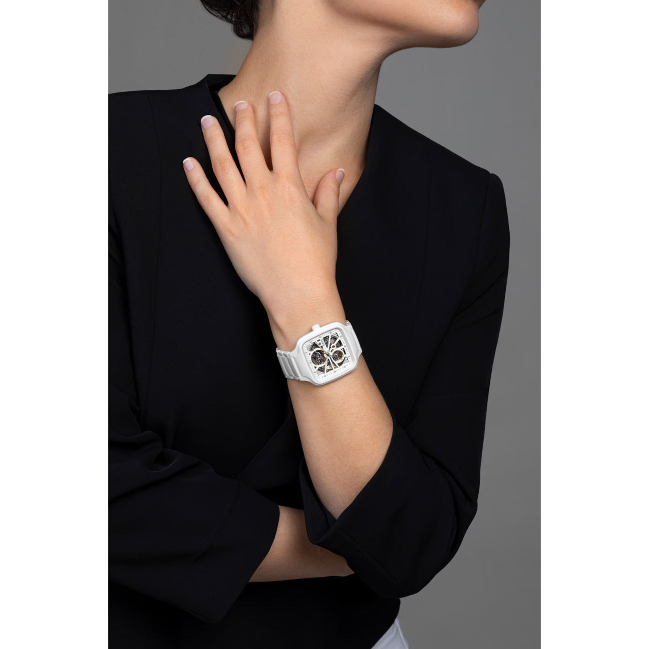 Modern square white wristwatch with visible skeleton dial on woman’s wrist