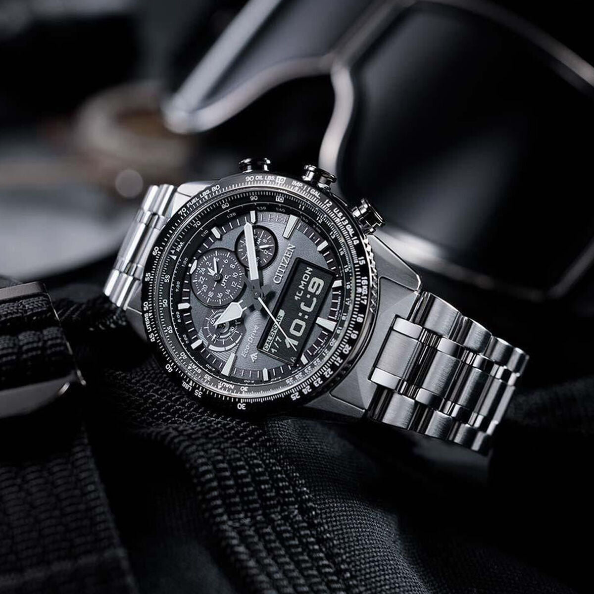 Stainless steel chronograph wristwatch with digital display on black fabric background