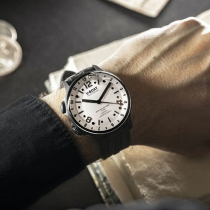 Caol na bhfear ag caitheamh faire dhiailiú mór bán le uimhreacha trom dubh agus strap dubh uigeach