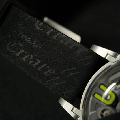 Nahaufnahme einer modernen Armbanduhr mit Metallgehäuse und schwarzem Armband mit eingraviertem Text