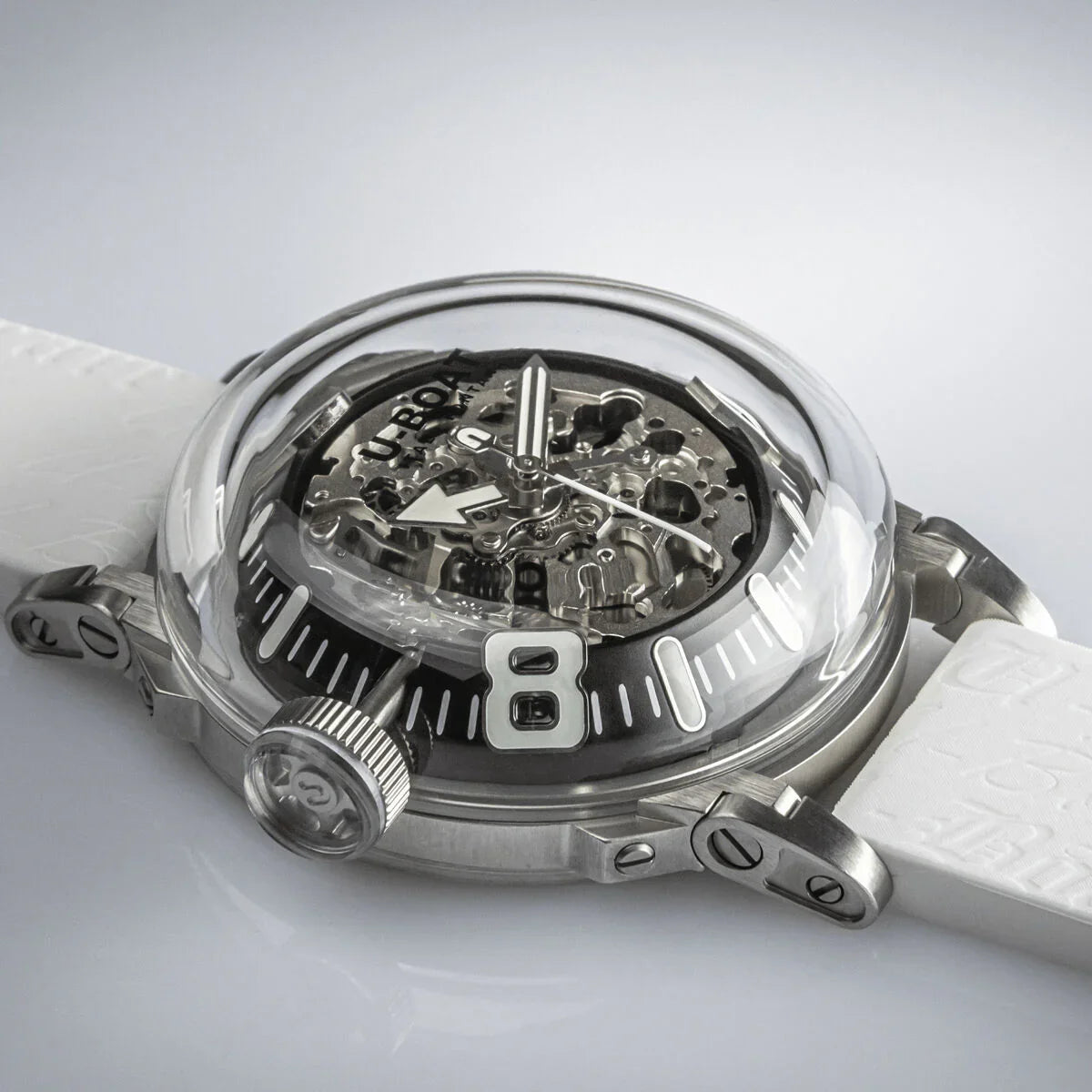 Skeleton dial luxury watch with domed crystal, large crown, and white strap on display
