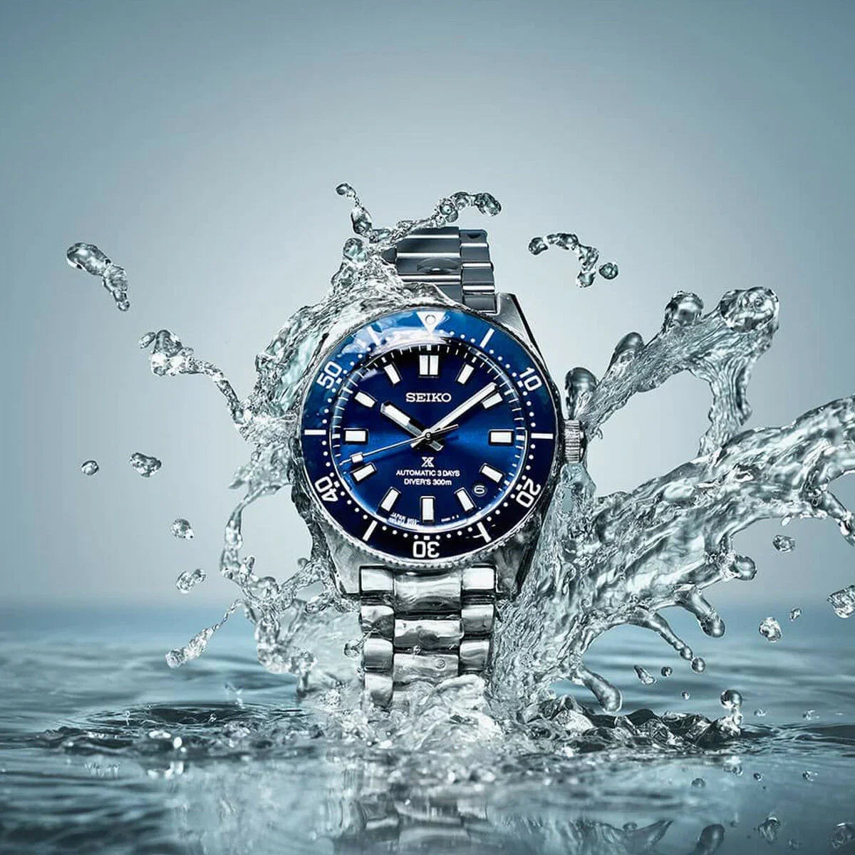 Orologio da polso subacqueo in acciaio inossidabile con quadrante blu che spruzza nell'acqua, che mostra l'impermeabilità.