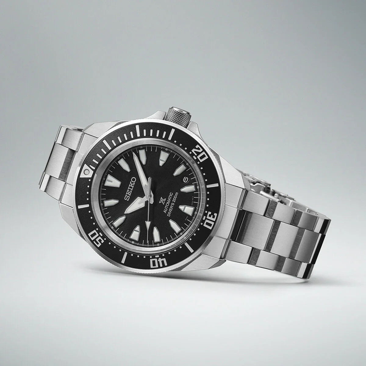 Stainless steel automatic dive watch with black dial and unidirectional bezel on gray background