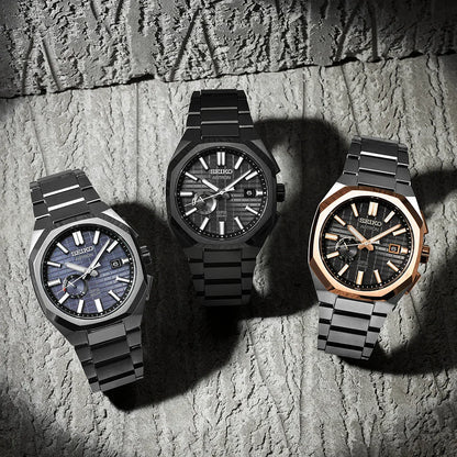 Three modern men's stainless steel watches with textured dials on a stone background