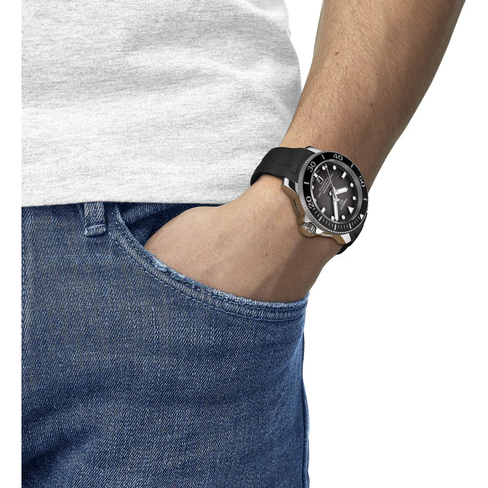Black diver watch with rotating bezel on wrist, casual outfit, hand in jeans pocket