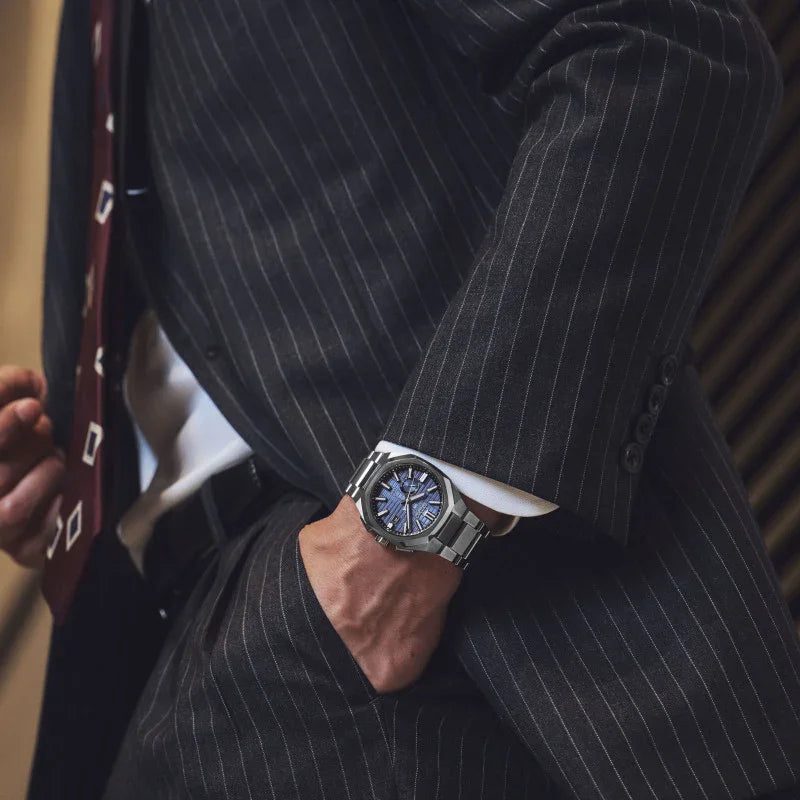 Man in pinstripe suit wearing titanium watch with blue dial and metal bracelet