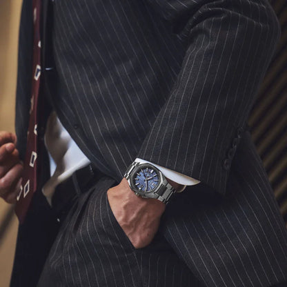Man in pinstripe suit wearing titanium watch with blue dial and metal bracelet